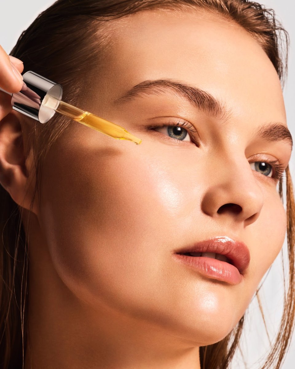 close up of a woman's face applying vitamin c
